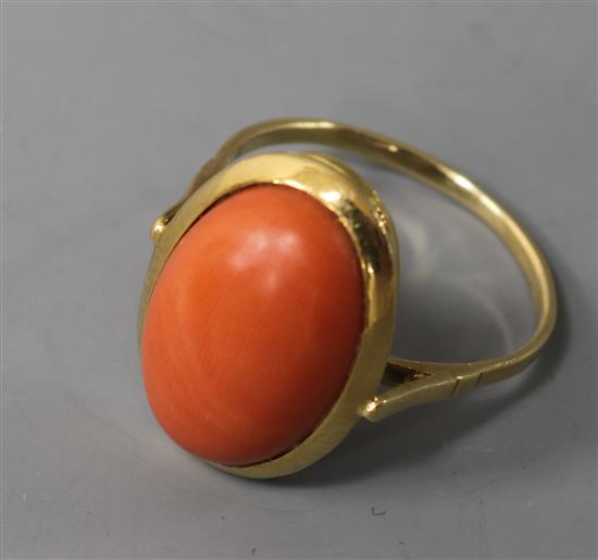 A yellow metal and oval cabochon coral ring, size R.